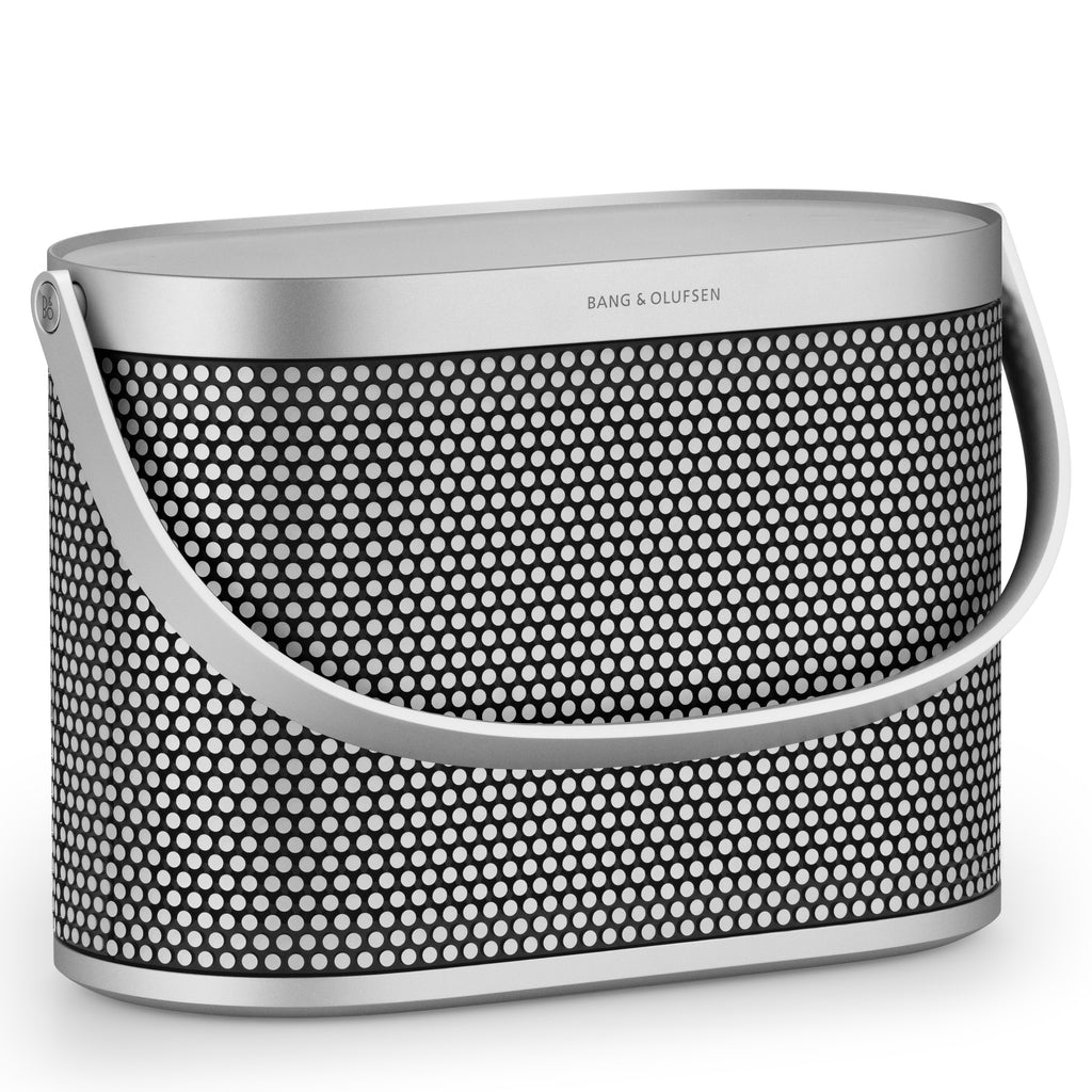 Perspektivische Ansicht des Bang & Olufsen Beosound A5 Spaced Aluminium – Design-Lautsprecher mit nach unten geklapptem Tragegriff und Fokus auf das ikonische lasergeschnittene Punktmuster.