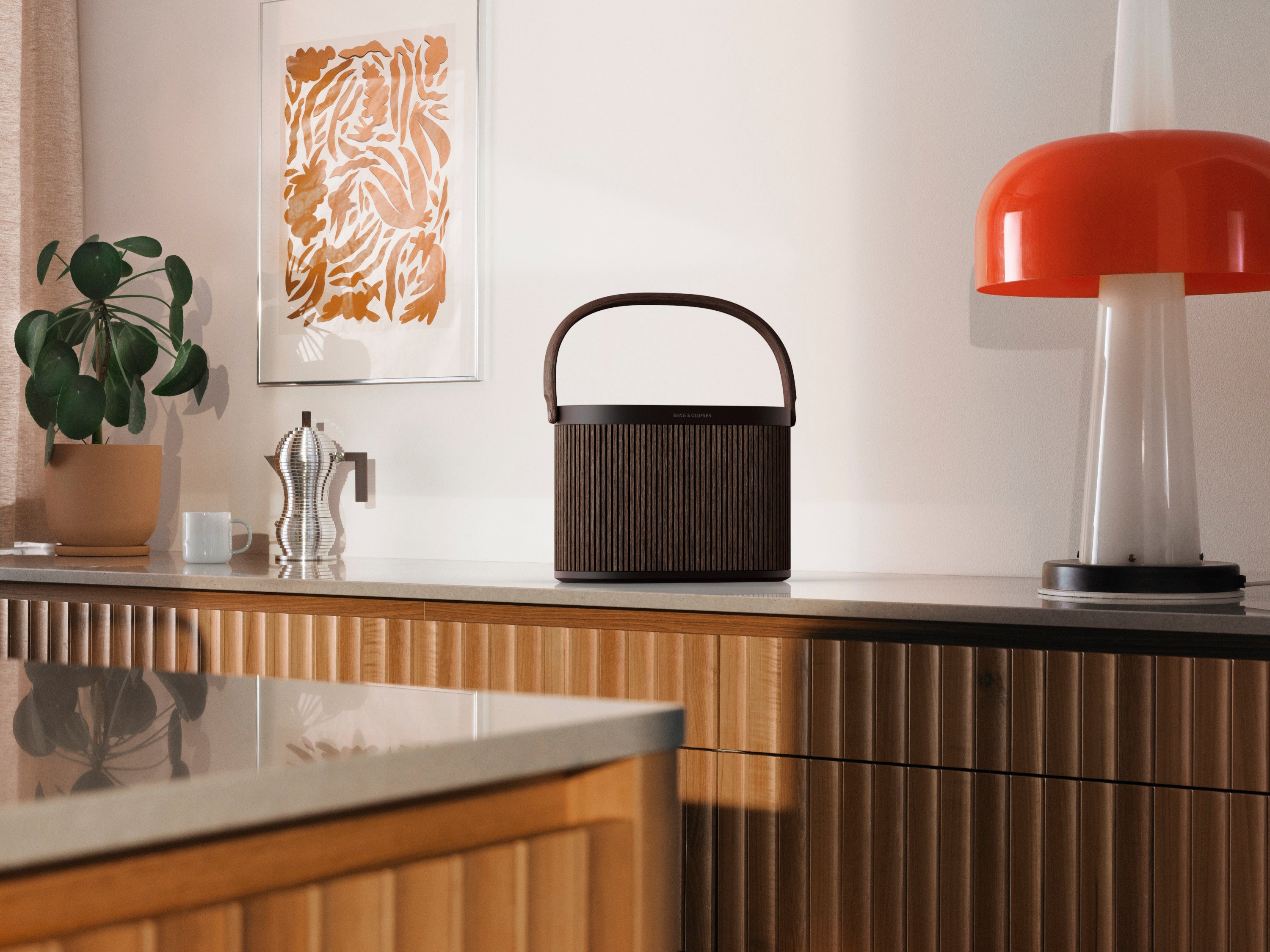 Bang & Olufsen Beosound A5 in dark oak auf einem Sideboard neben einer Lampe