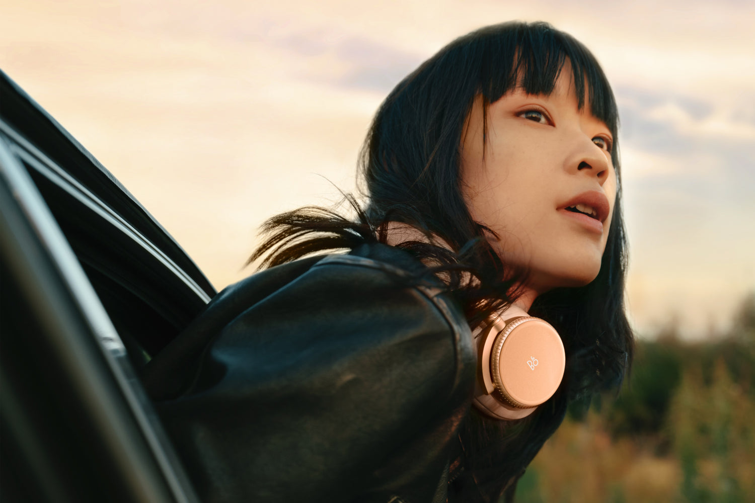 Bang & Olufsen Beoplay H100 in sunset apricot um den Nacken einer Frau