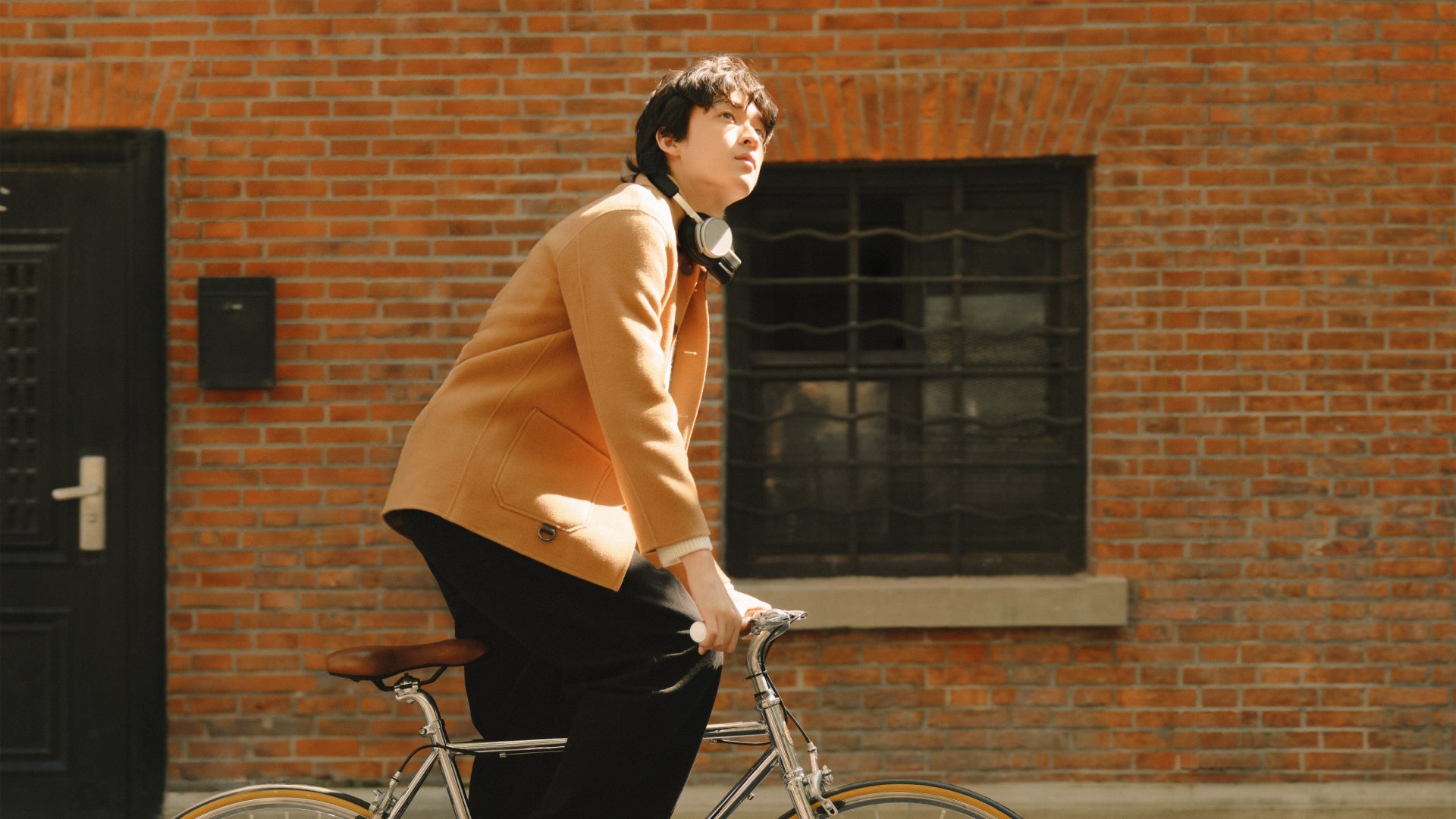 B&O Beoplay H100 infinity black an Nacken eines Mannes auf einem Fahrrad