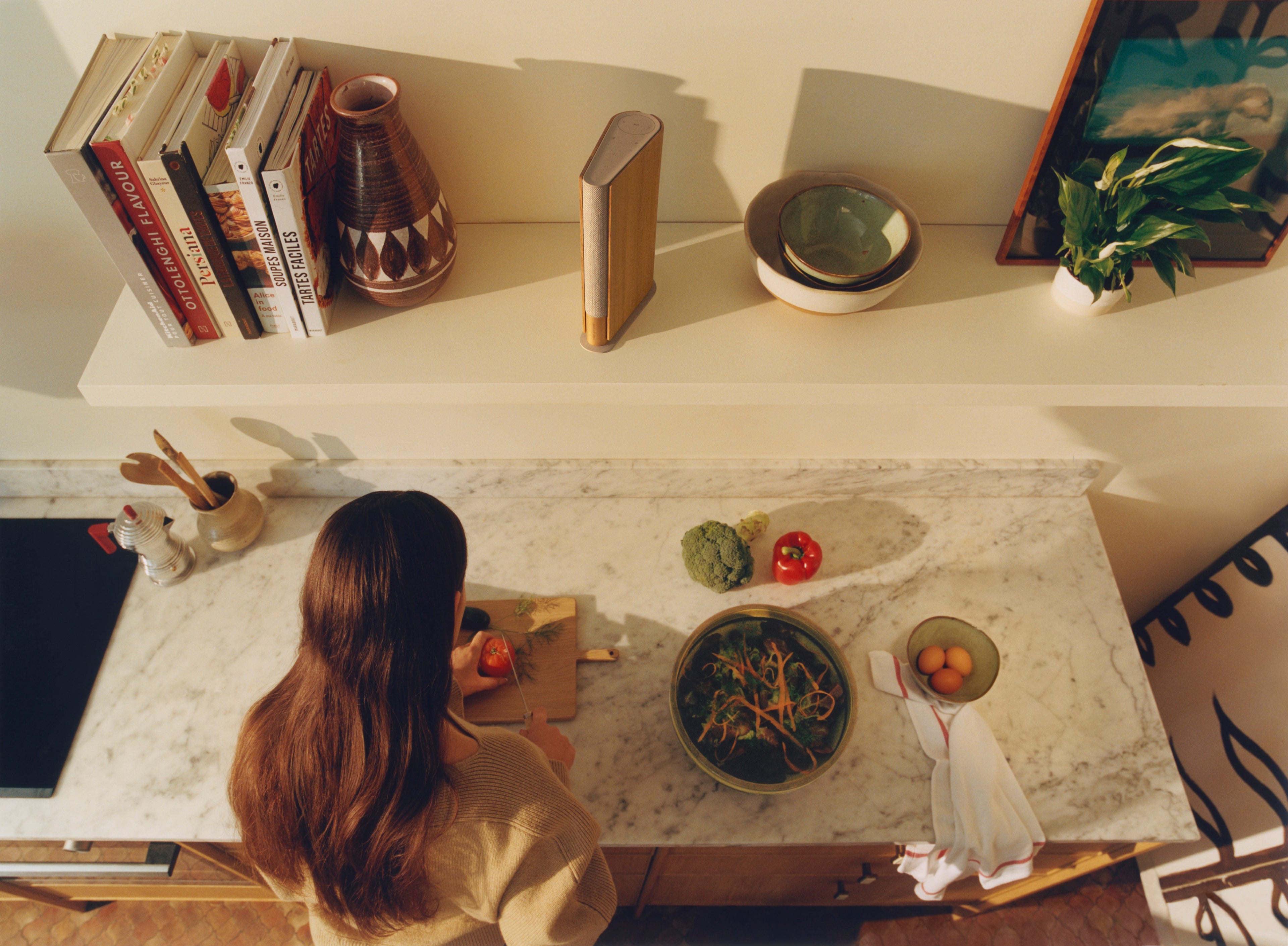 Bang & Olufsen Beosound Emerge Regallautsprecher auf einem Board neben Büchern 